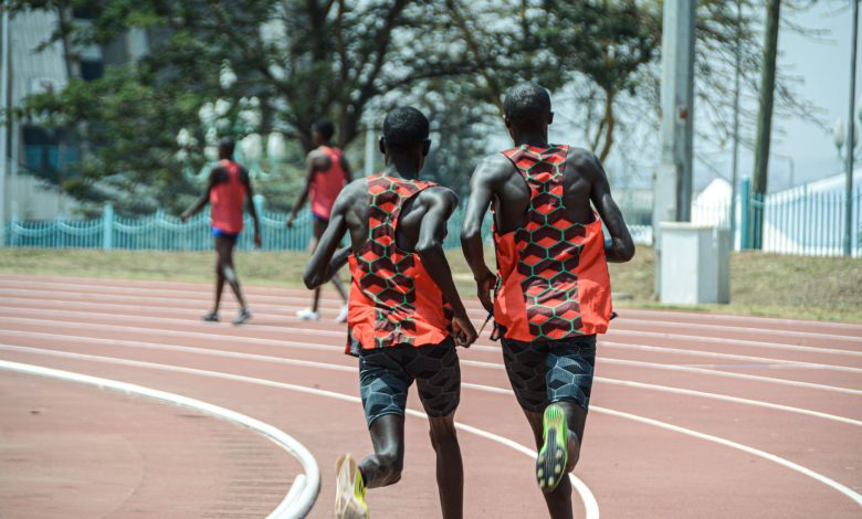 Dois atletas correm lado a lado em uma pista de atletismo em Nairobi, no Quênia.