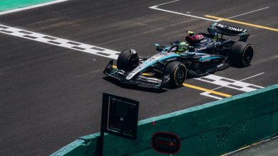 Carro de Fórmula 1 cruza a linha de chegada em um circuito durante uma corrida diurna
