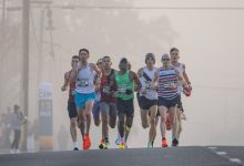 Corredores disputam uma prova de rua em meio à neblina, em cenário urbano.