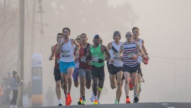 Corredores disputam uma prova de rua em meio à neblina, em cenário urbano.